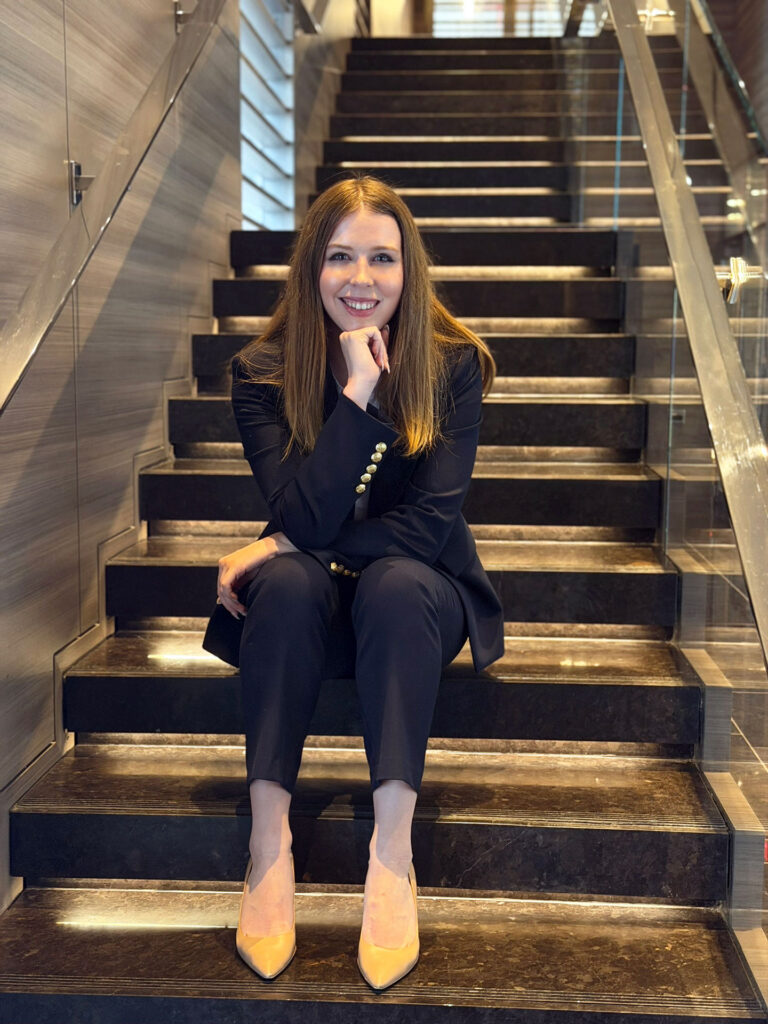 Grace Dunn seated confidently on marble stairs in a navy blazer — founder of Crownridge Coaching and elite one-on-one SAT, ACT, and PSAT tutor